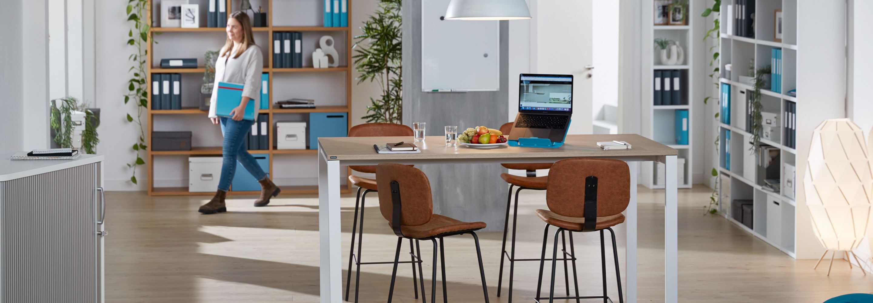 Une femme se promène dans un bureau avec un classeur.