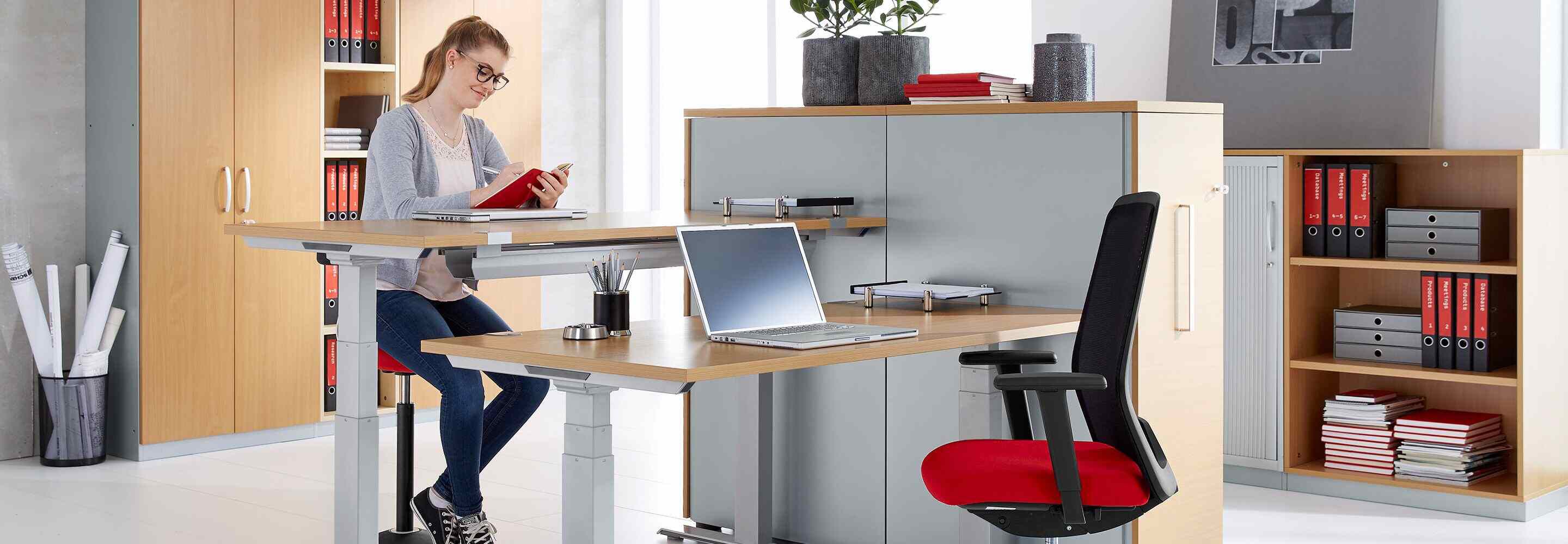 Une femme est assise à un bureau et écrit dans un carnet.