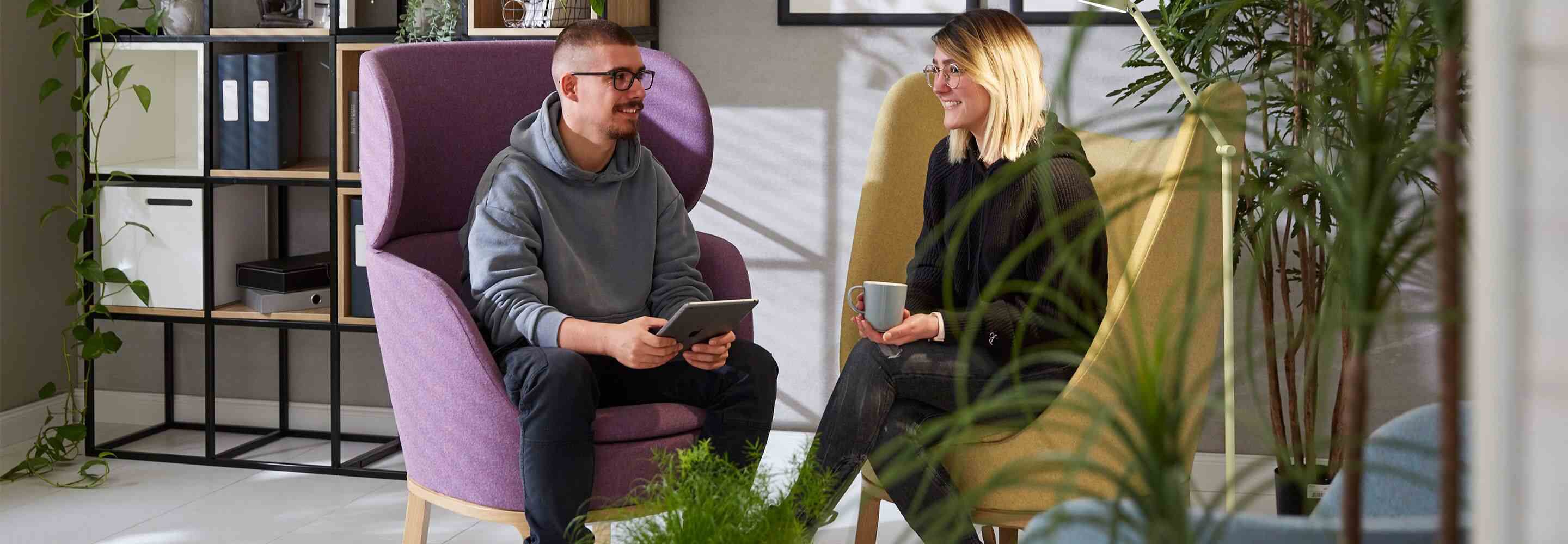 Ein Mann und eine Frau sitzen in Sesseln nebeneinander und unterhalten sich.