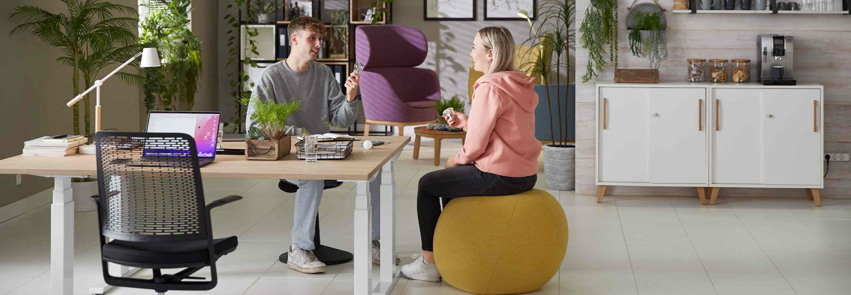 Eine Frau und ein Mann, der eine Glühbirne in der Hand hält, unterhalten sich an ihrem Arbeitsplatz im Büro.