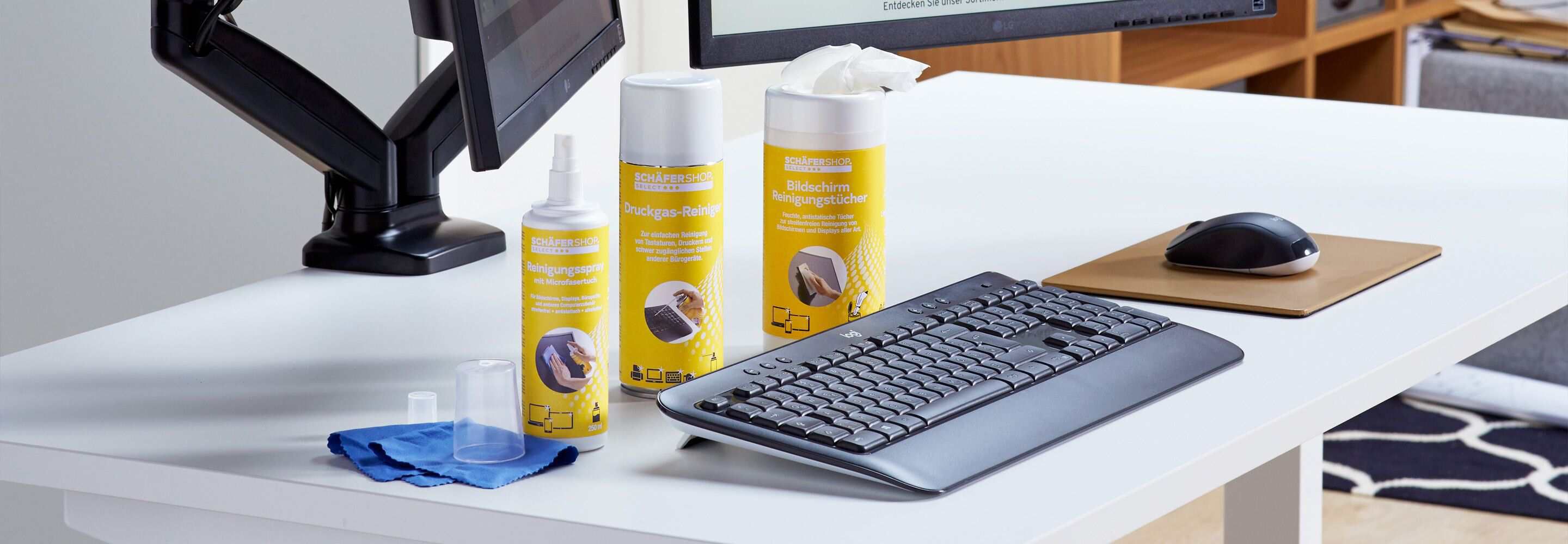 Een toetsenbord en een muis liggen op een bureau. Ernaast liggen verschillende schoonmaakmiddelen.