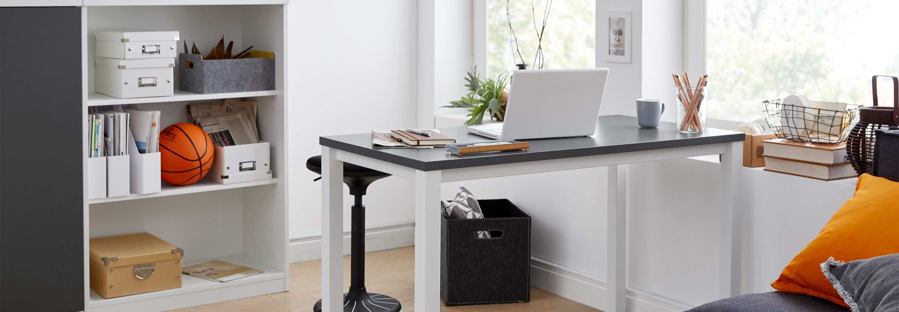 Een licht kantoor met een bureau, een plank en een bank.