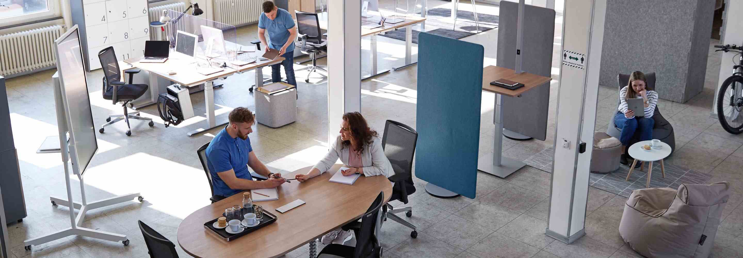 Een vrouw en een man zitten aan een bureau en wisselen ideeën uit.