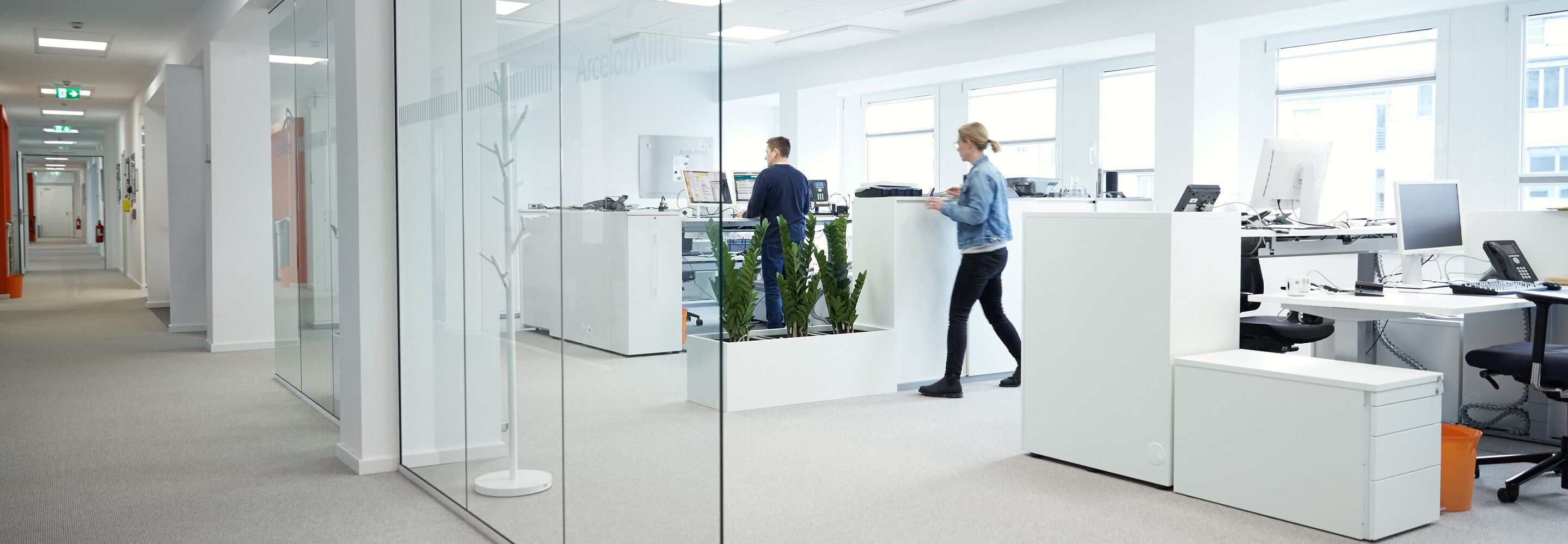 Twee mensen werken in een open kantoorruimte.