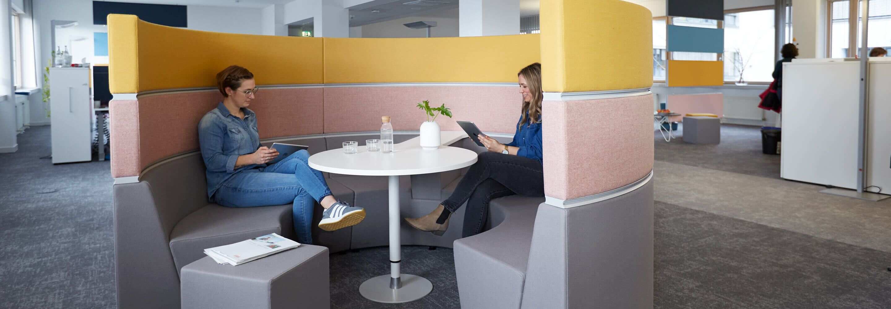 Twee vrouwen zitten in een vergaderzaal met tablets. 