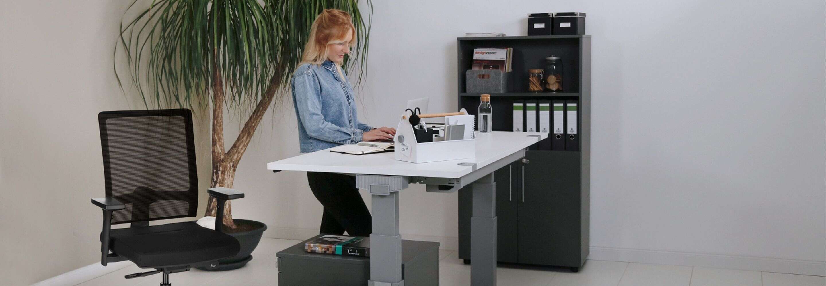 Een vrouw staat achter een bureau en werkt op een laptop.