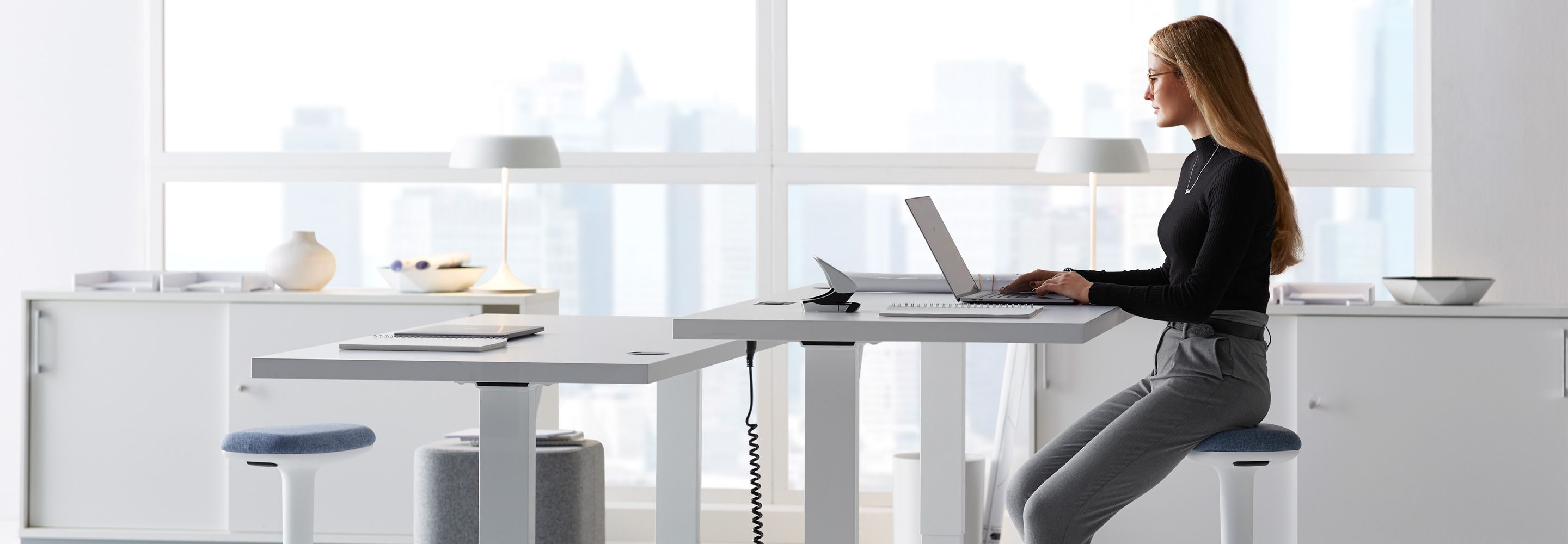 Une femme est assise à un bureau et travaille sur un ordinateur portable. 