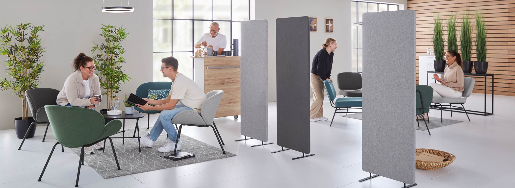 Freundliche Mitarbeitende in modernem Pausenraum mit Lounge-Möbeln und Kaffeestation