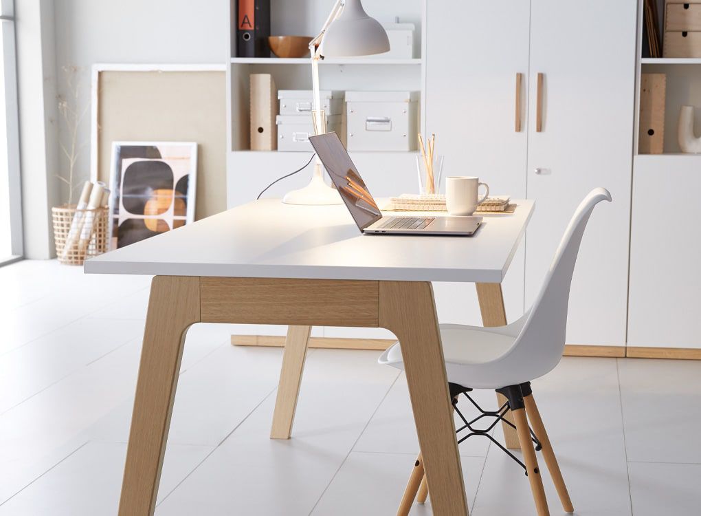 Schreibtisch mit Laptop, Lampe und Accessoires in minimalistischem Büro-Setup