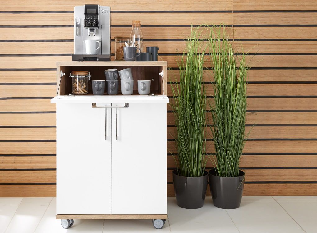 Moderner Kaffeeautomat auf rollbarem Schrank mit Tassen und Deko im Pausenraum