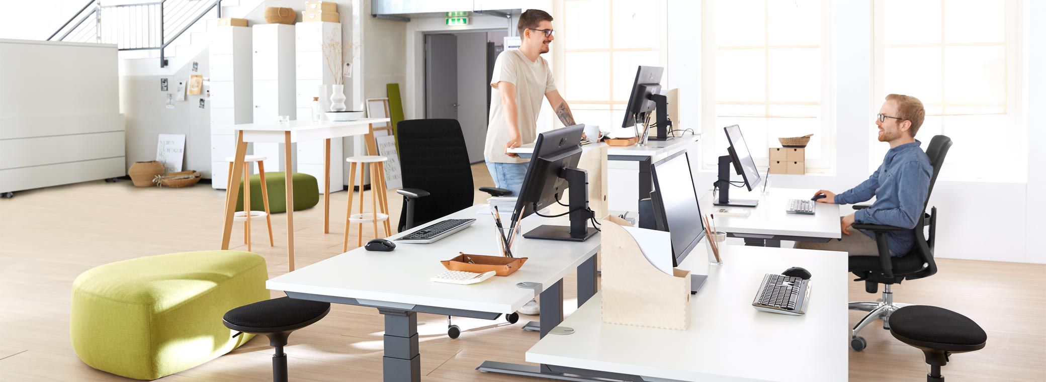 Zwei Personen arbeiten in unterschiedlichen Bereichen des Multispace-Bueros und
stehen sich gegenueber
