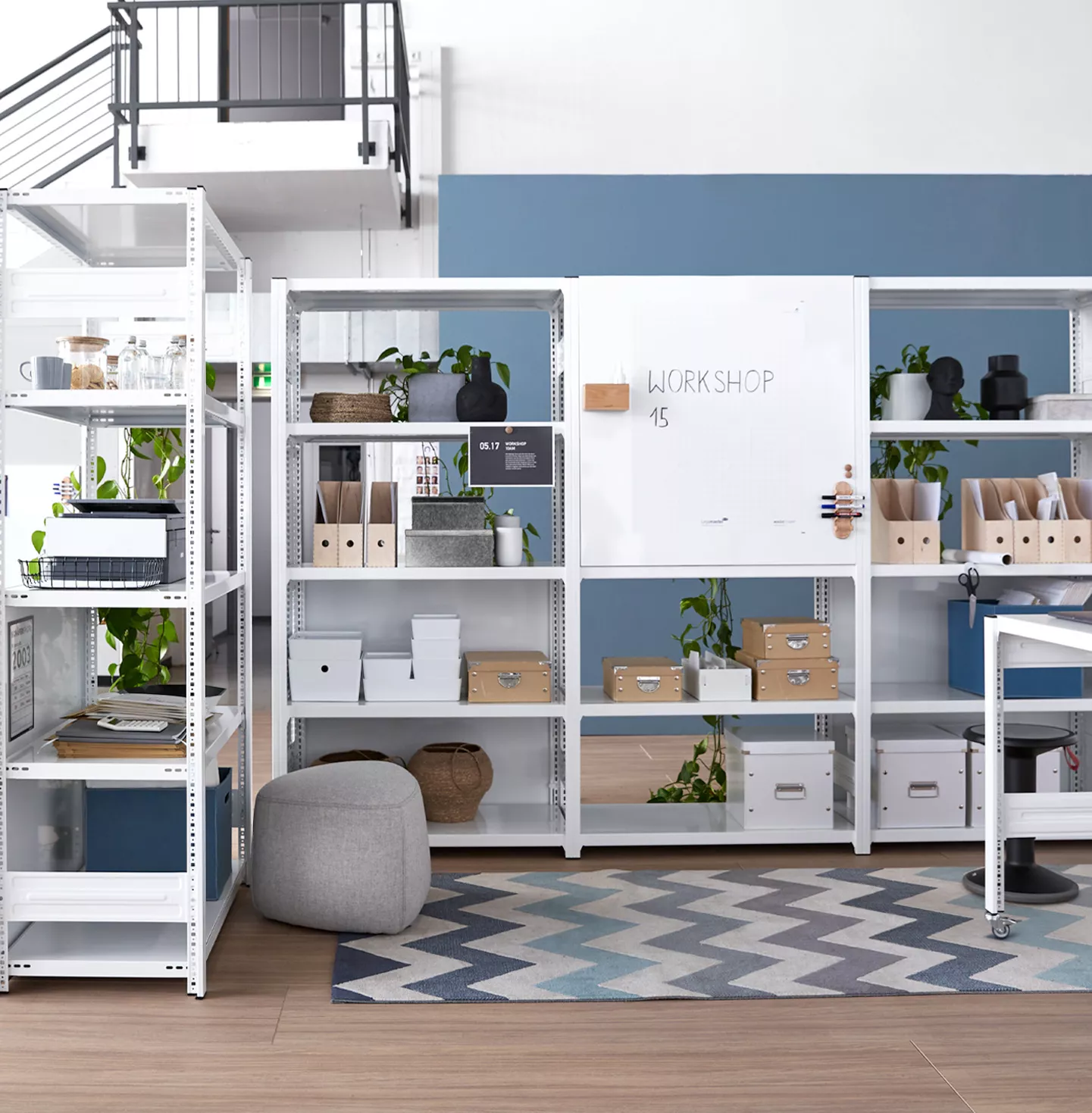 Weißes Regalsystem in einem Raum, ausgestattet mit Pflanzen, Aufbewahrungsboxen und einer Workshoptafel.