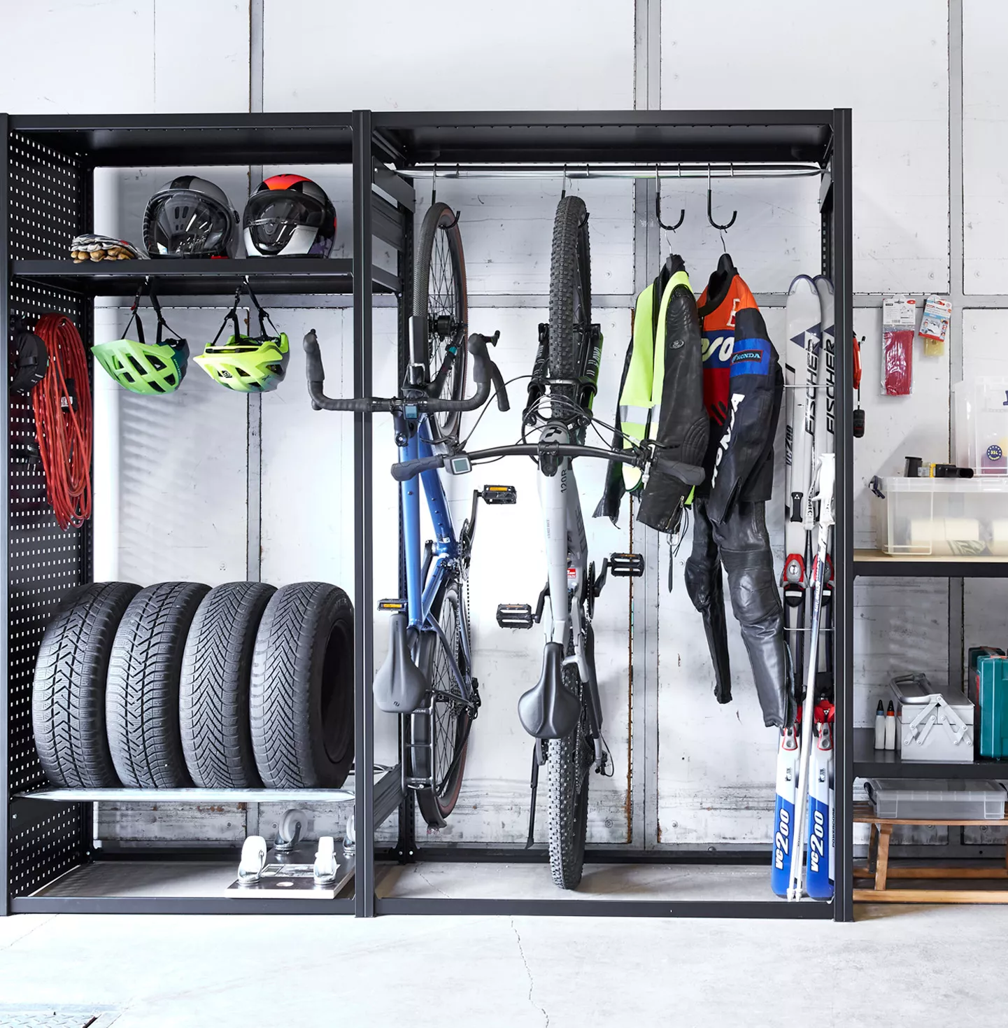 Schwarzes Regalsystem in einer Garage, ausgestattet mit Fahrraedern, Sportausrüstung und Werkzeugkisten.