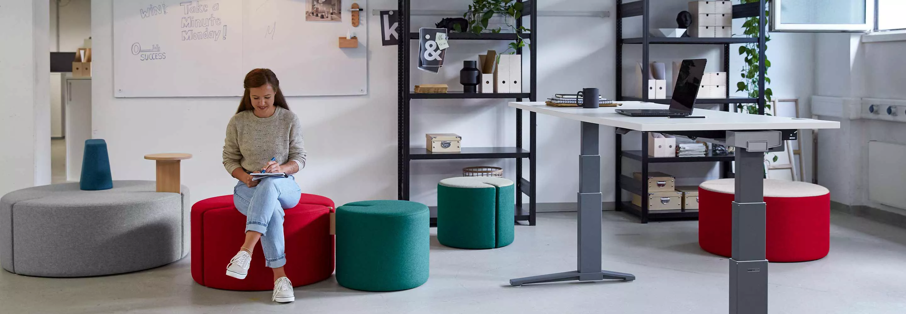 Eine Frau, die in einem Einzelbüro auf einem roten Hocker sitzt