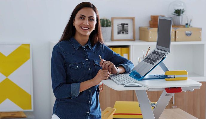 Eine lächelnde Person, die am ergonomisch eingerichteten Schreibtisch steht