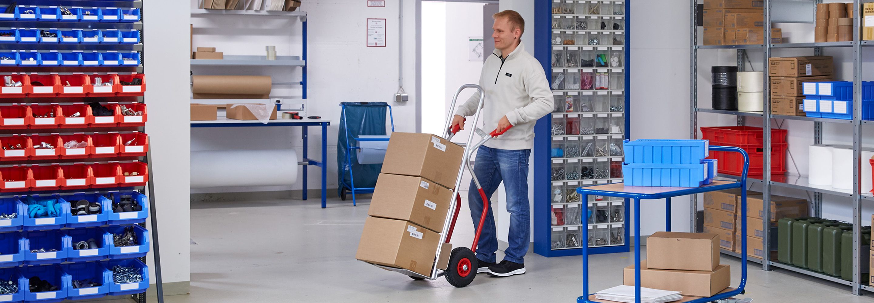 Person die eine Sackkarre durch ein Lagerraum schiebt