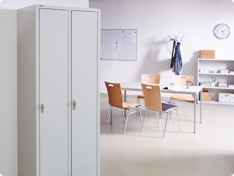 Pausenraum im Lager mit Spind im Vordergrund und Tisch mit Stühlen im Hintergrund