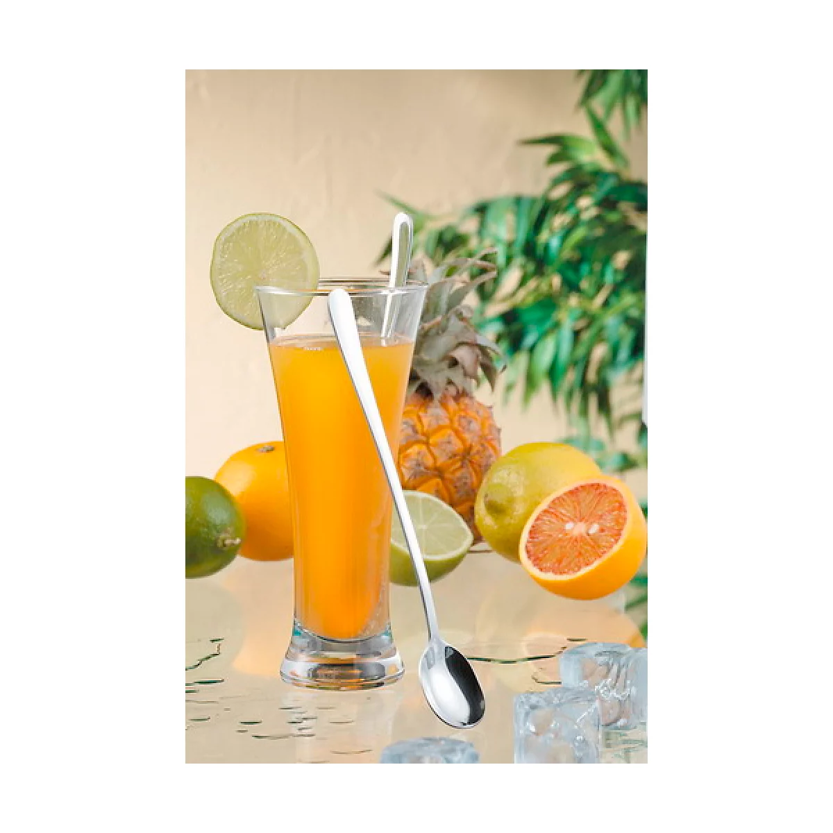 Ein Glas Orangensaft mit Limettenscheibe und Löffel, umgeben von Zitrusfrüchten und Ananas.