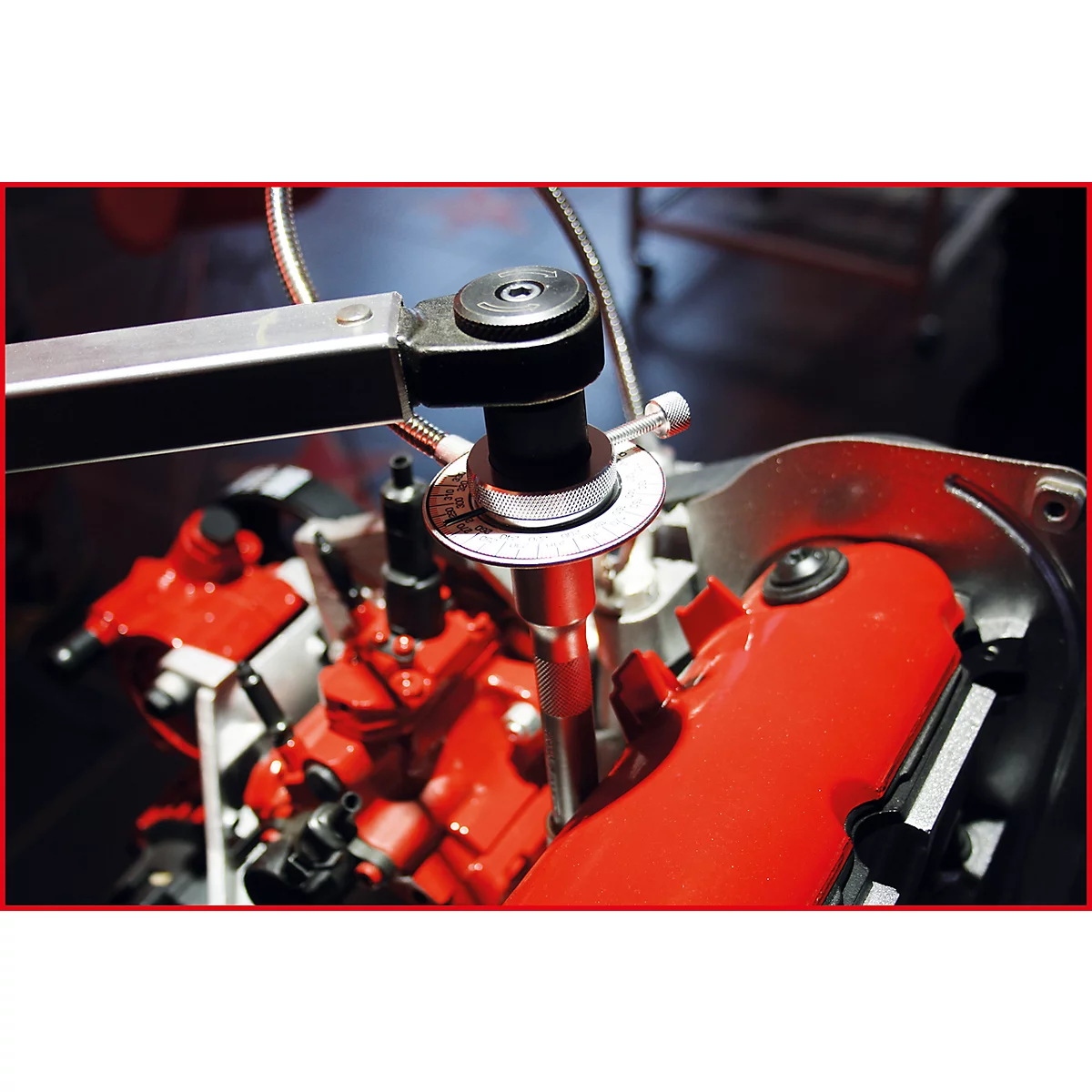 Nahaufnahme eines roten Motorblocks mit Werkzeug. Das Werkzeug scheint für Wartungs- oder Reparaturarbeiten am Motor verwendet zu werden.