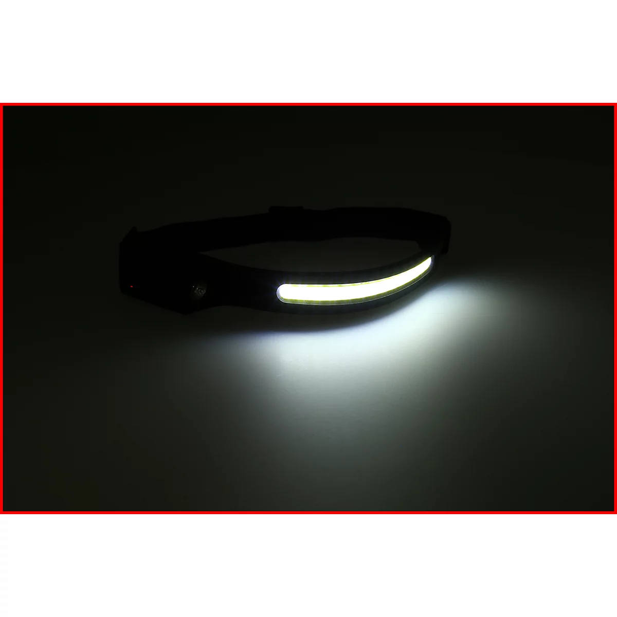 Eine schwarze Stirnlampe mit leuchtend weißem Licht, das sich auf einer Oberfläche ausbreitet.