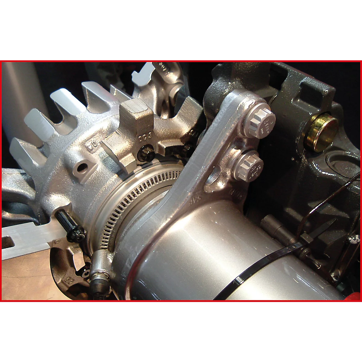 Nahaufnahme einer Metallkonstruktion mit Zahnrad und Schrauben. Die Detailaufnahme zeigt metallische Oberflächen und technische Elemente.