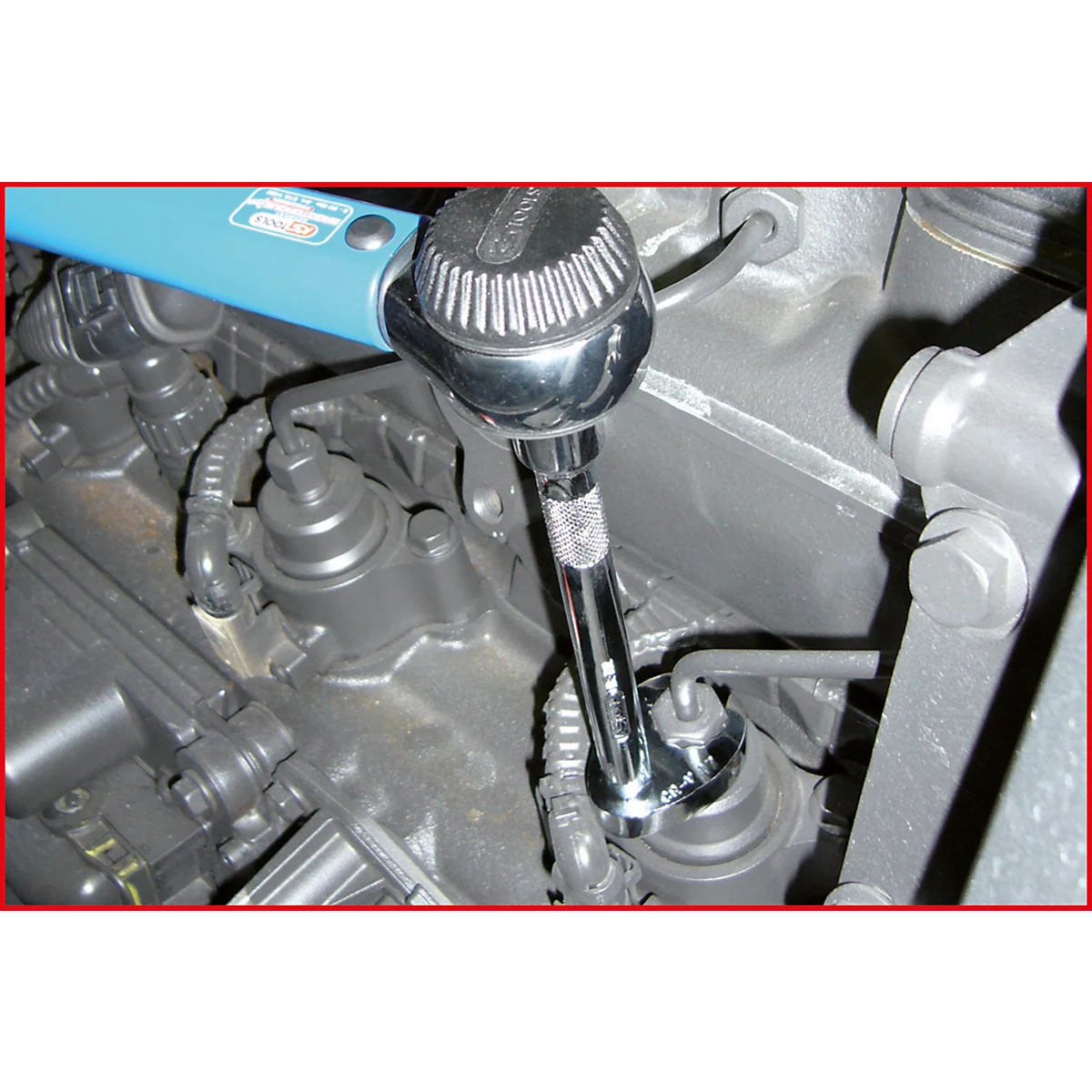 Eine Hand hält einen Schraubenschlüssel und arbeitet an einem Motorteil.