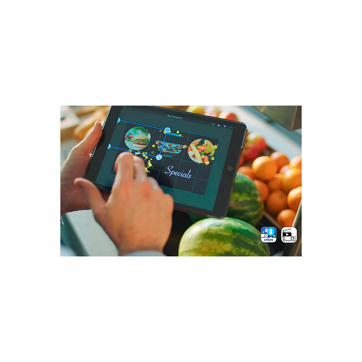 Hands holding tablet with menu app, menu displays "Specials" with images of dishes, watermelon, oranges in background.