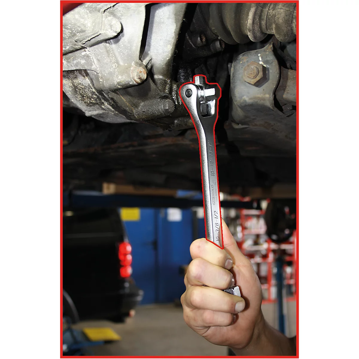 Ein Mechaniker schraubt mit einem Schraubenschlüssel an einem Fahrzeug. Der Schraubenschlüssel ist auf einen Bolzen unter dem Fahrzeug gerichtet.