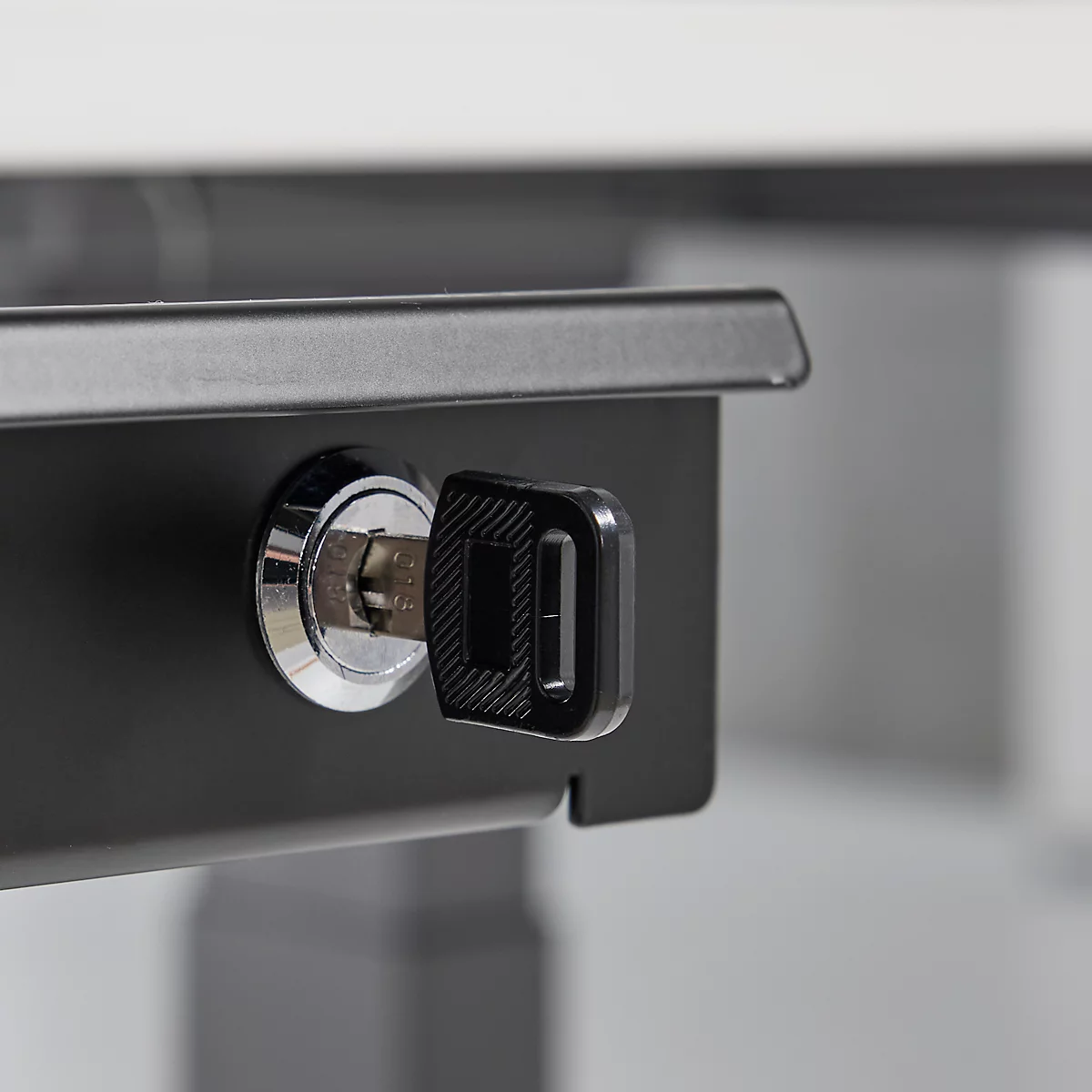 Close-up van een sleutel in een zwart slot op een meubelstuk. De sleutel is gedeeltelijk ingestoken.