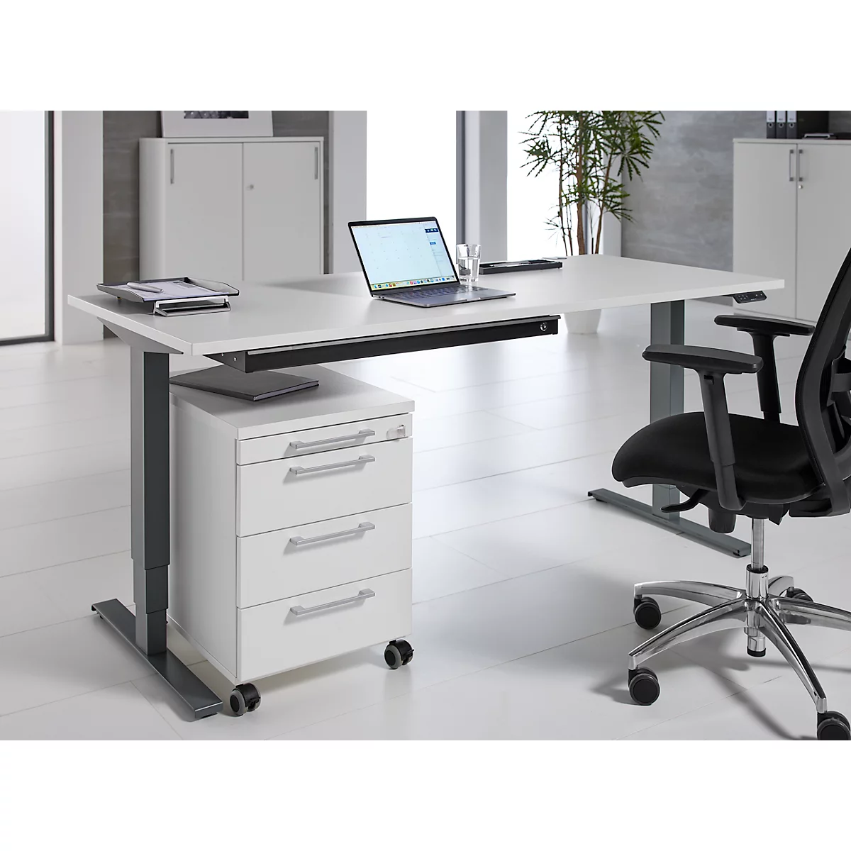 Bureau met laptop en bureaustoel tegen een witte achtergrond. Ladekast.