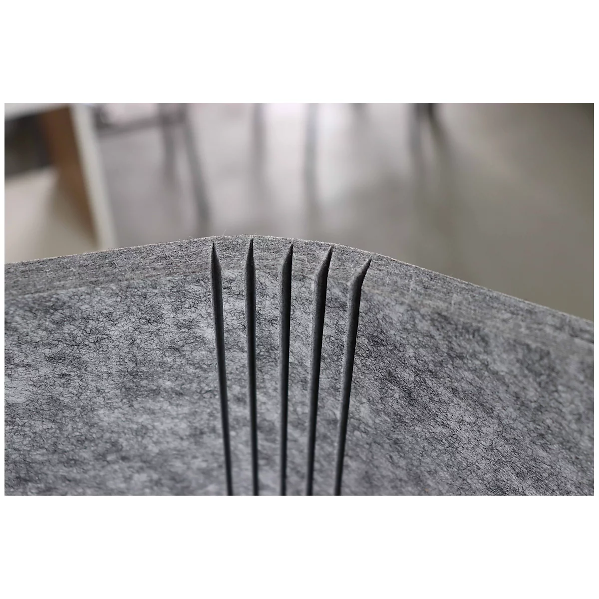 Grey felt material with six vertical cuts, forming thin strips.