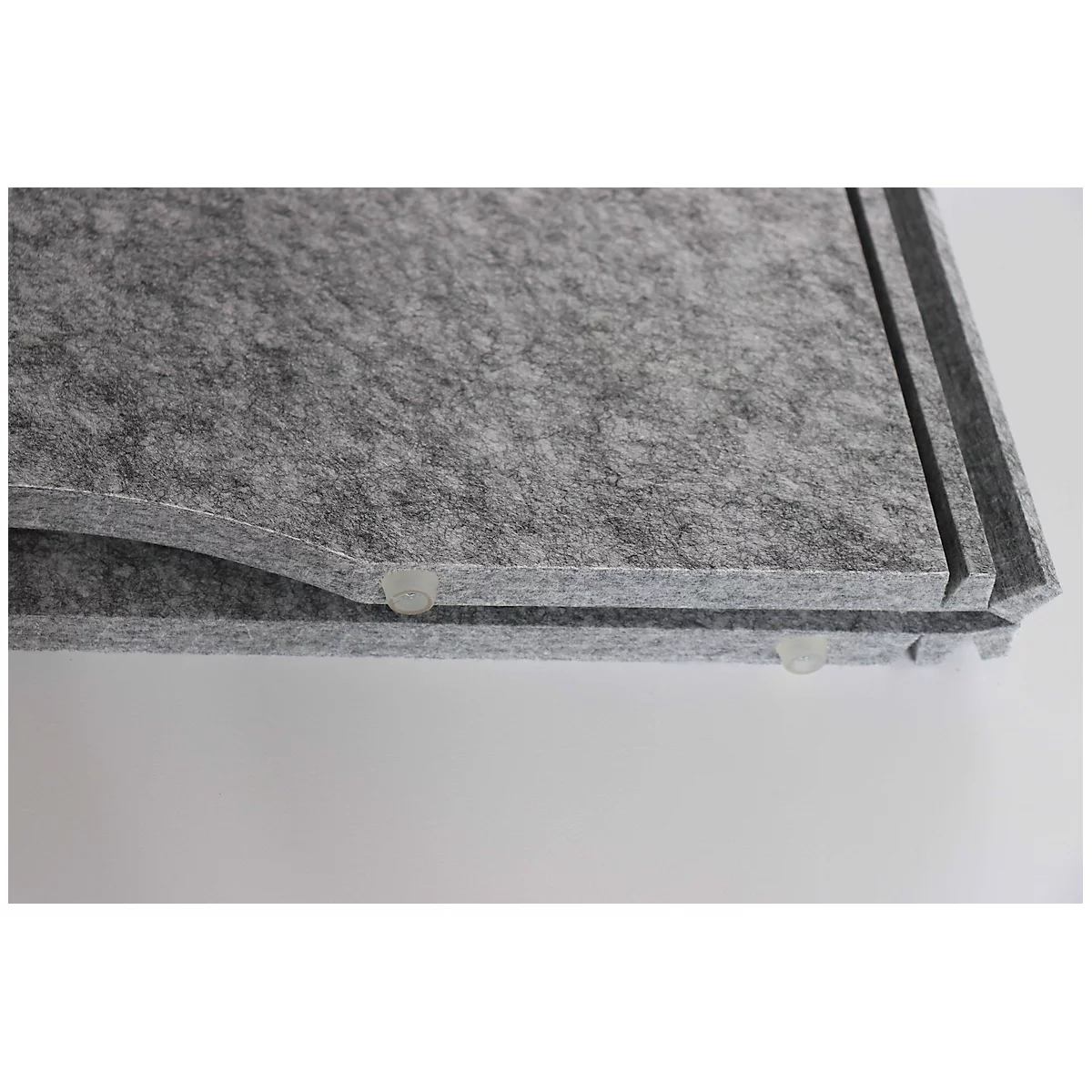 Close-up of grey felt. The corners are rounded, small transparent plastic feet underneath.