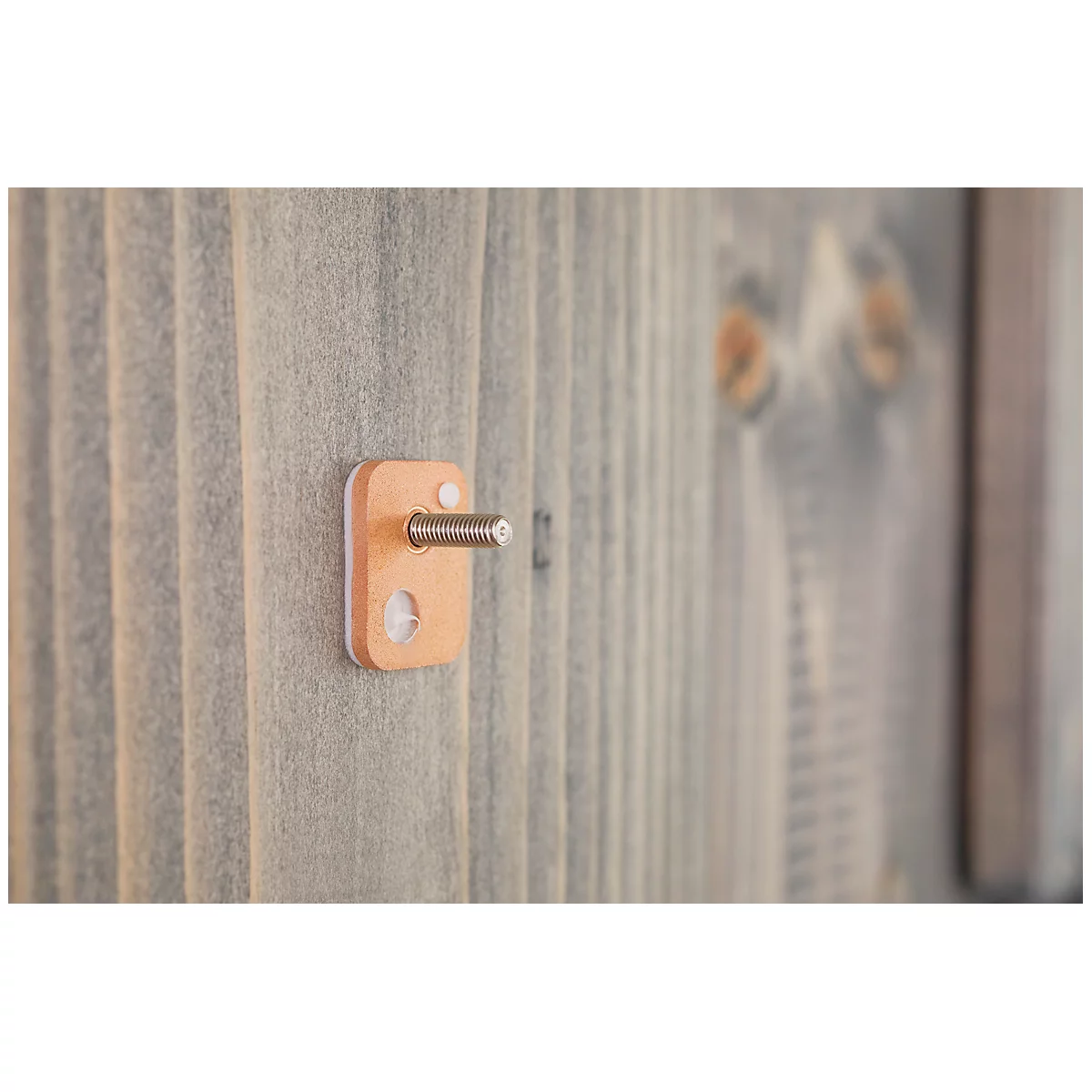 Close-up of a small, light brown wooden block with screw attached to a vertical wooden plank.