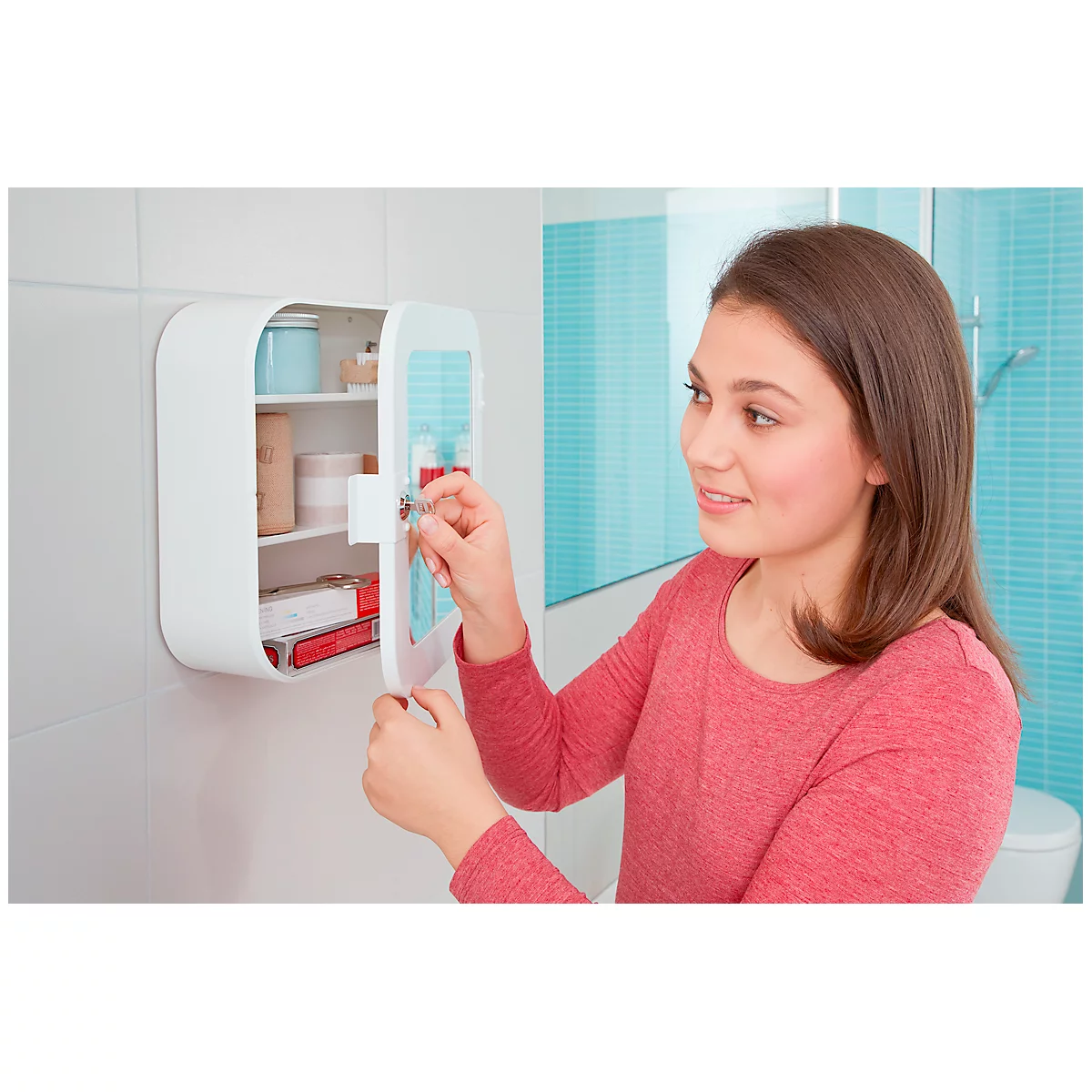 A girl opens a white medicine cabinet in the bathroom. She smiles as she opens the cabinet door.