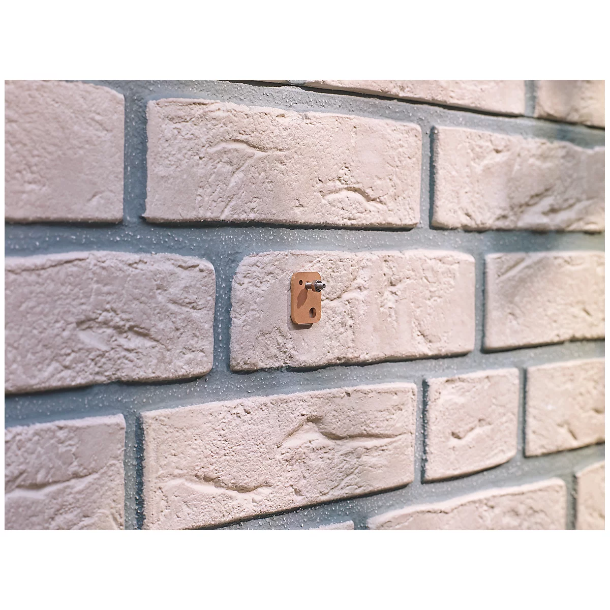 Close-up of a brick wall with a brown hook. The bricks are light gray, the joints are blue.