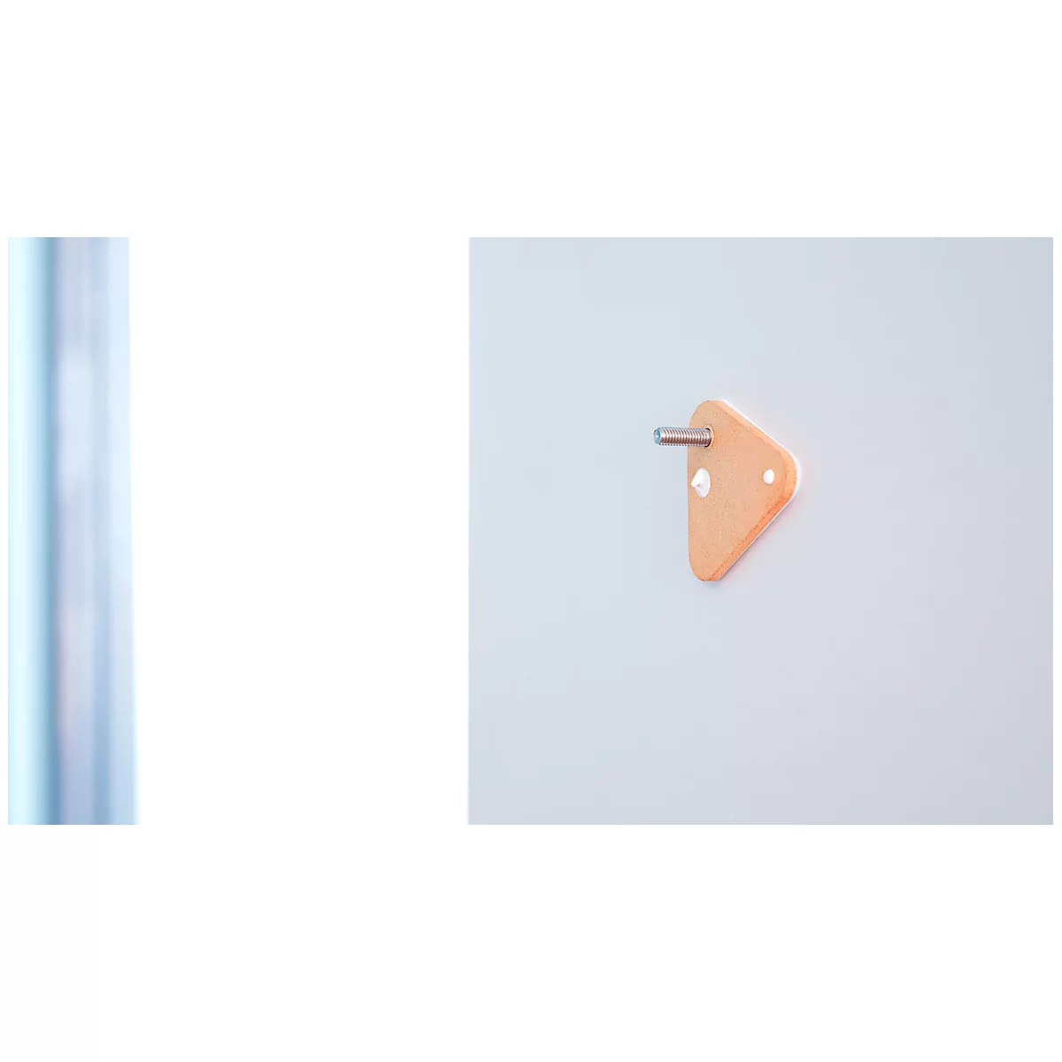 Orange triangular element with metal pin, attached to a white wall.