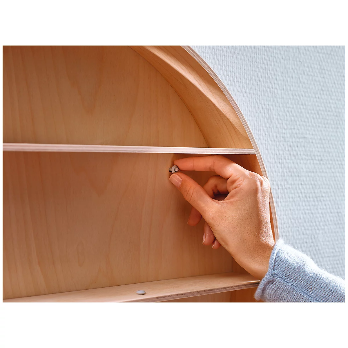 Close-up of a hand inserting a small dowel into a wooden structure.