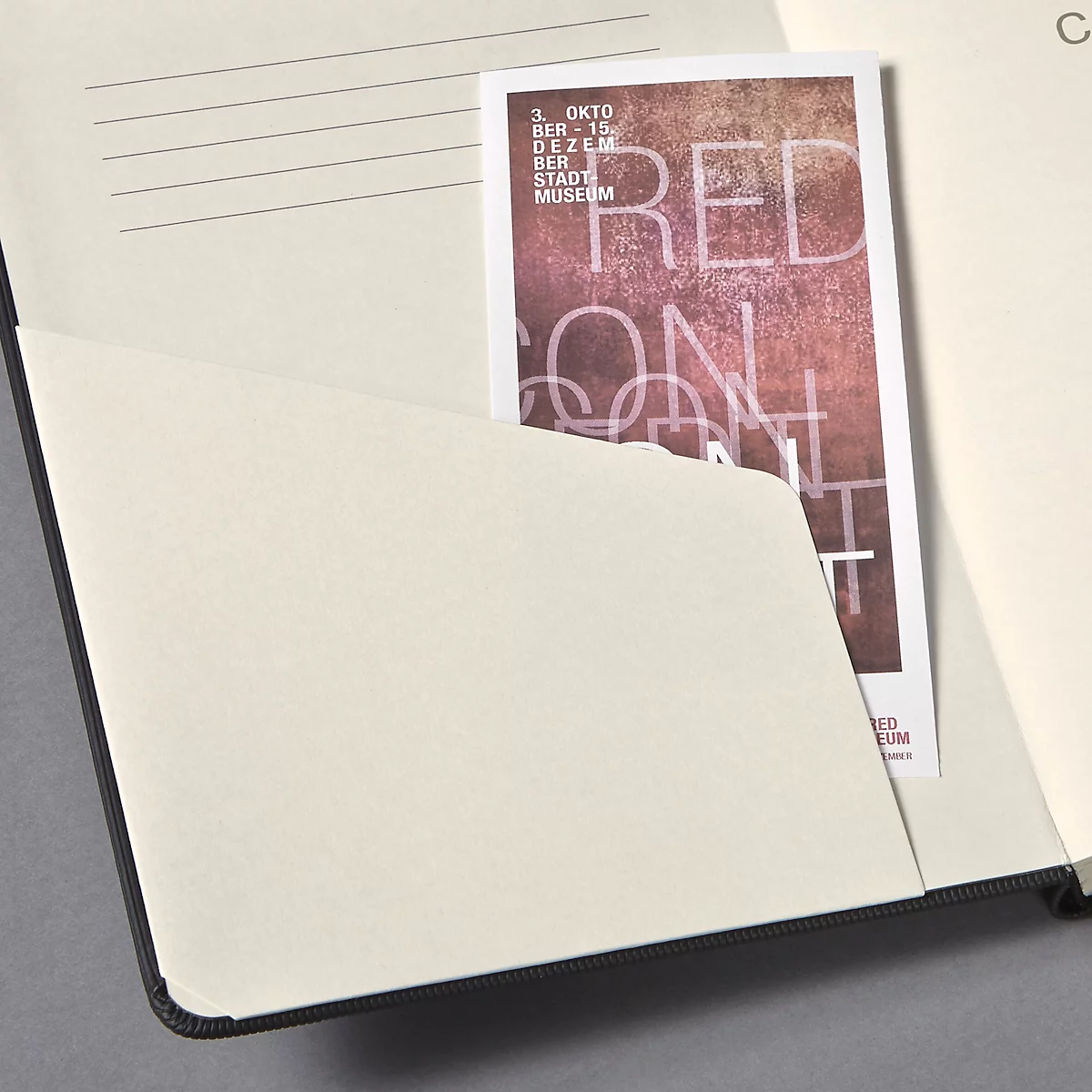 Un carnet ouvert avec une carte de visite dans la poche intérieure. La carte indique "RED ON ART".