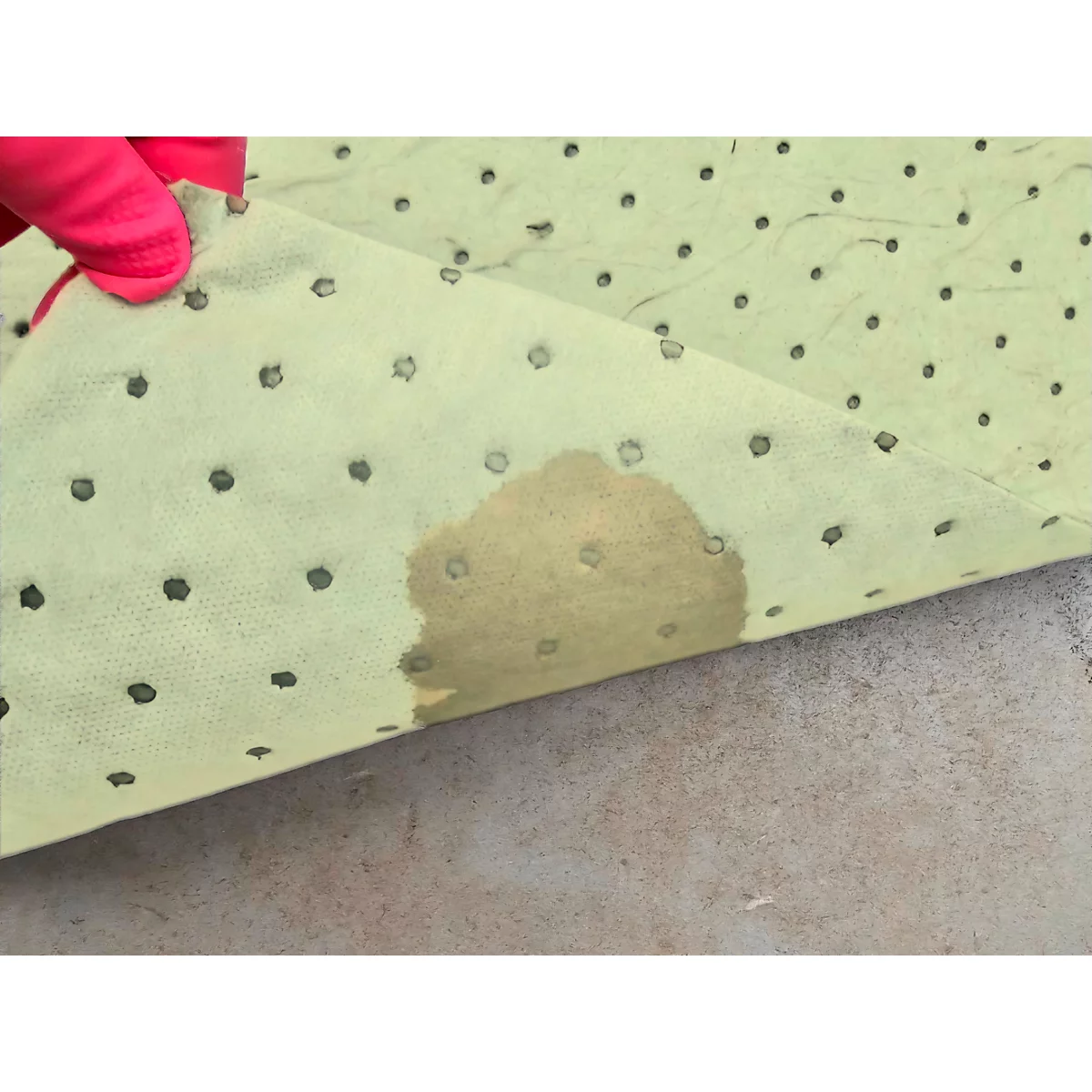 Un paño absorbente amarillo con una mancha de líquido, sostenido por una mano enguantada de color rosa.