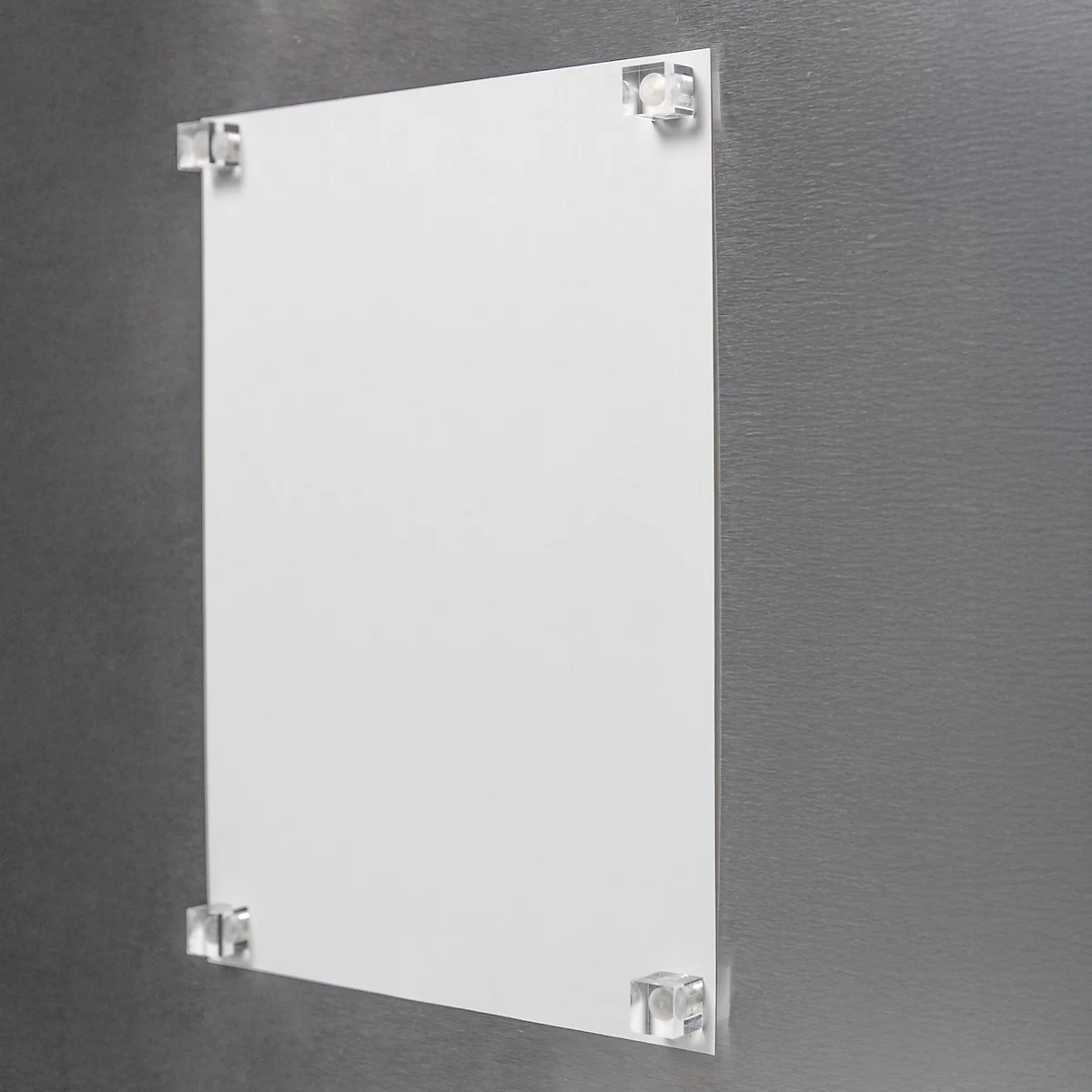 Une feuille de papier blanche, fixée à un mur gris avec des supports transparents.