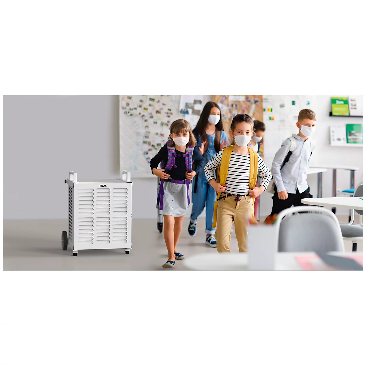 Schoolchildren with masks leaving a classroom. In the foreground is a white air purifier.