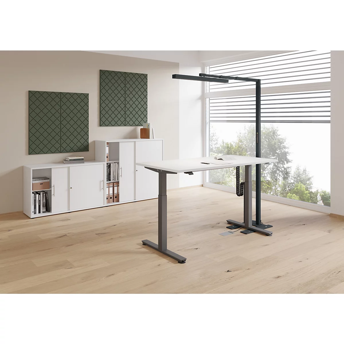 Kantoor met in hoogte verstelbaar bureau, lamp en kasten. Lichte houten parketvloer en groene wandpanelen.