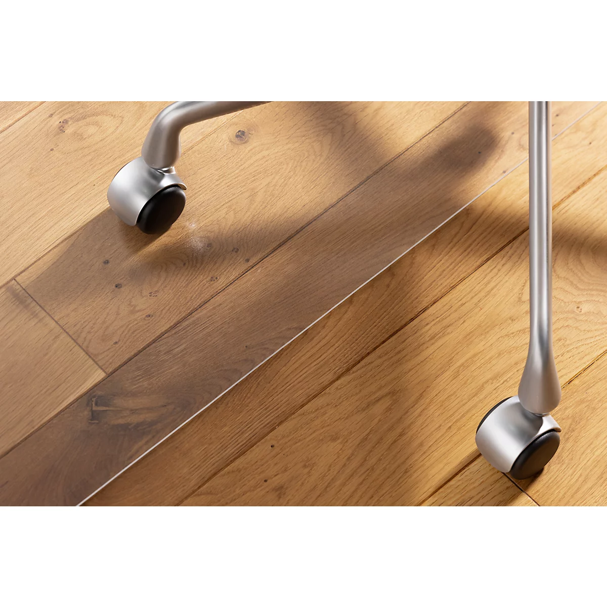 Primer plano de ruedas de silla sobre un piso de madera. Las ruedas metálicas tienen ruedas negras.