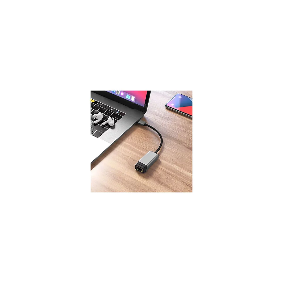 Ein grauer Ethernet-Adapter steckt in einem Laptop auf einem Holztisch.