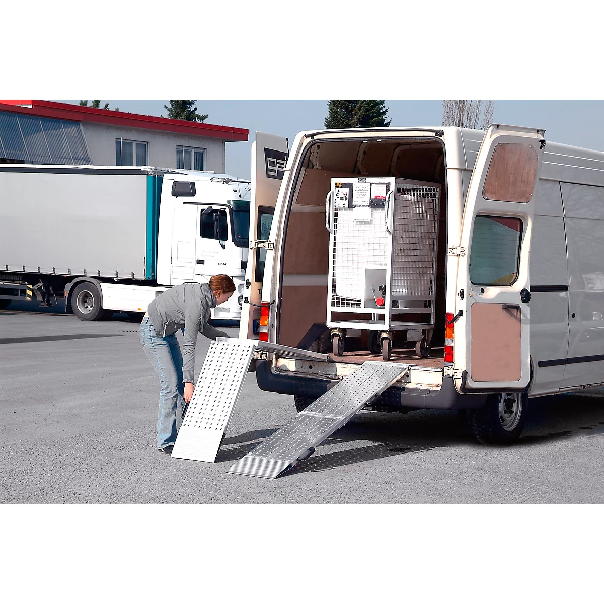 A man is positioning a ramp on a van. A rolling crate is inside the van.