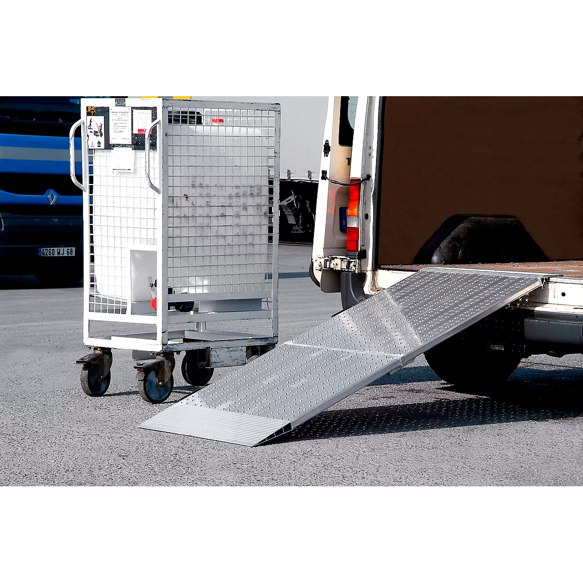 Grey roll cage next to an extended loading ramp of a delivery van.