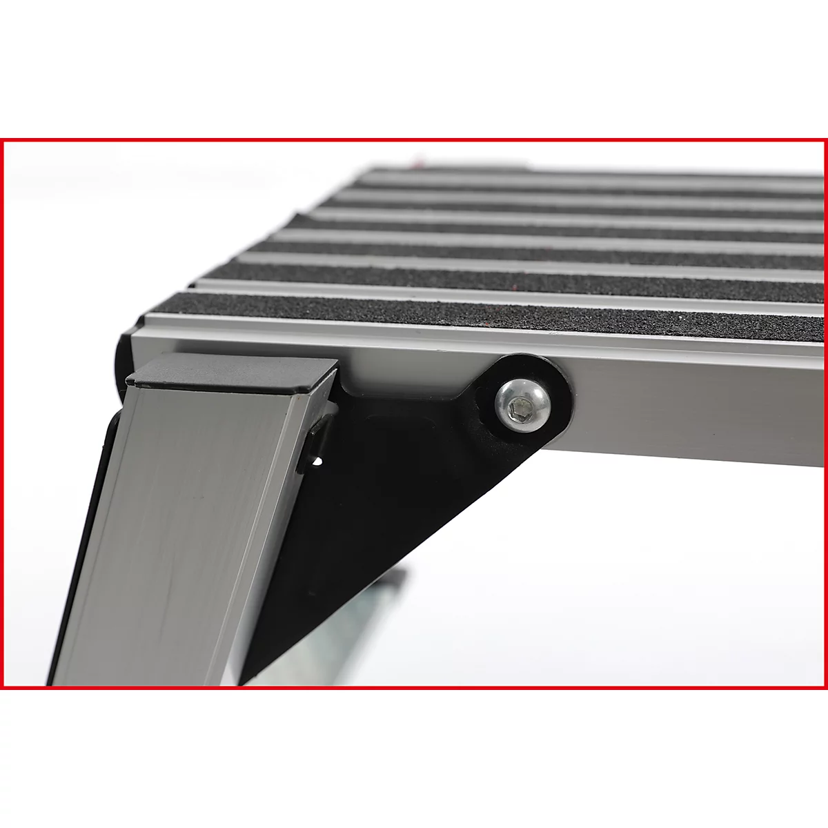 Detailaufnahme einer Aluminium-Trittstufe mit schwarzer rutschfester Oberfläche und sichtbaren Verschraubungen.