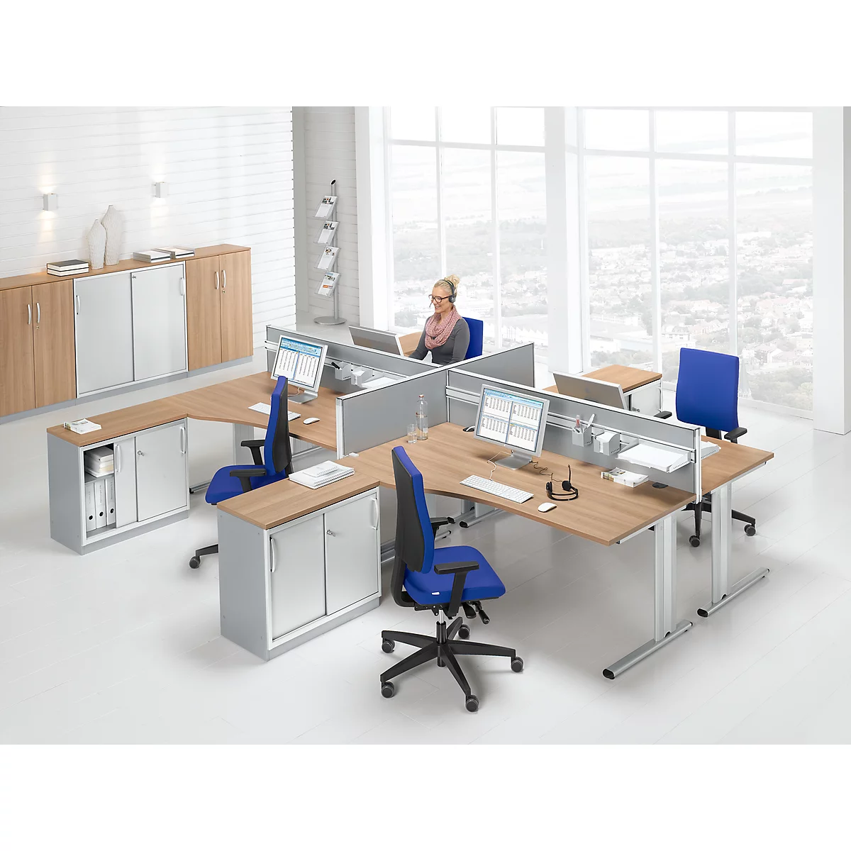 Office with desks, chairs, cabinets and a woman at the computer.
