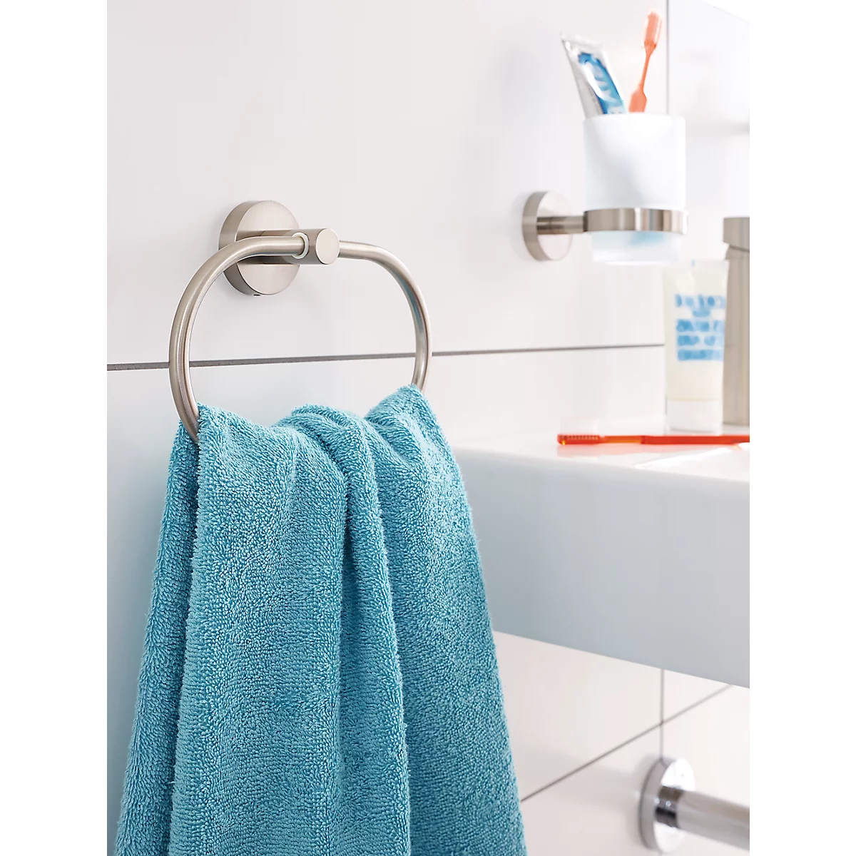 Serviette bleue sur un porte-serviettes argenté dans une salle de bain. À côté, un porte-savon.