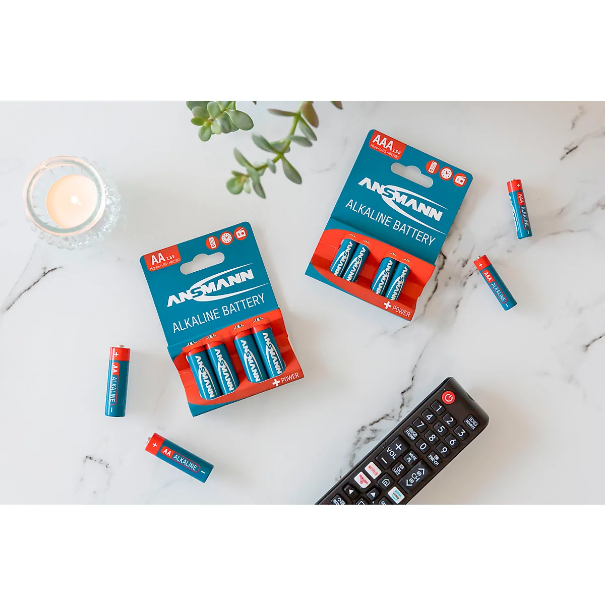 Top view of batteries and remote on white marble table. Batteries, packaged in blue and white, lie next to loose AAA batteries.